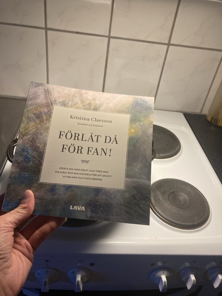 Boken Förlåt då för fan av författaren Kristina Claesson. Här visar hon sin bok framför en gammal spis dvs vitvaror.